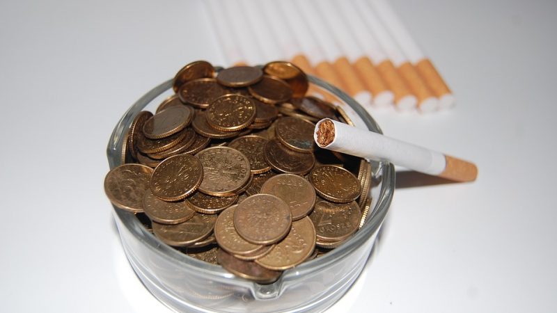 Cigarette with ash tray full of coins